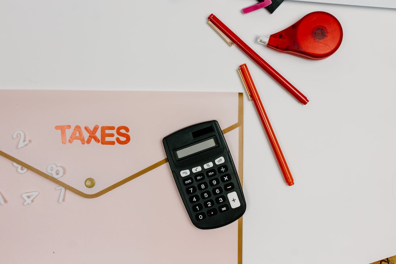 Flat lay image featuring a calculator, pens, and a folder labeled TAXES, perfect for finance-related themes.